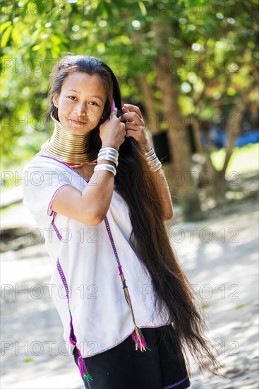 Young Kayan hill tribe woman does her hair in the morning