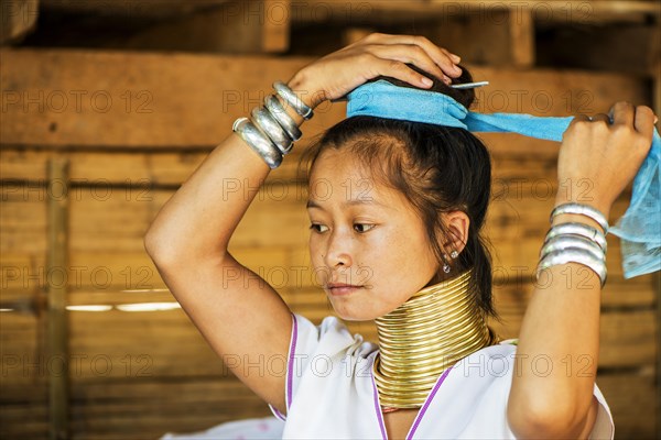 Young Kayan hill tribe woman does her hair in the morning