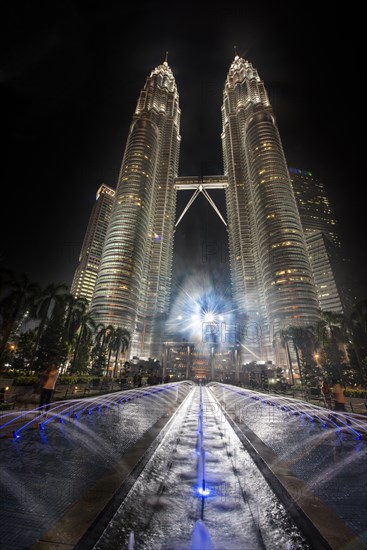 Fountain in front of illuminated Petronas Twin Towers at night