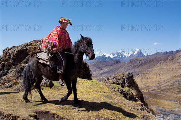 Indio mountain guide with colorful poncho riding on horseback