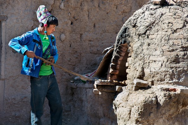 Boy with Chullo preparing breakfast in traditional oven