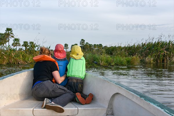 Mother with two small children with life jackets watching animals in a boat