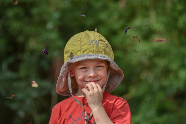 Small boy surrounded by flying colorful butterflies