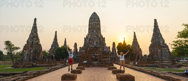 Two tourists jumping in front of a Buddhist temple