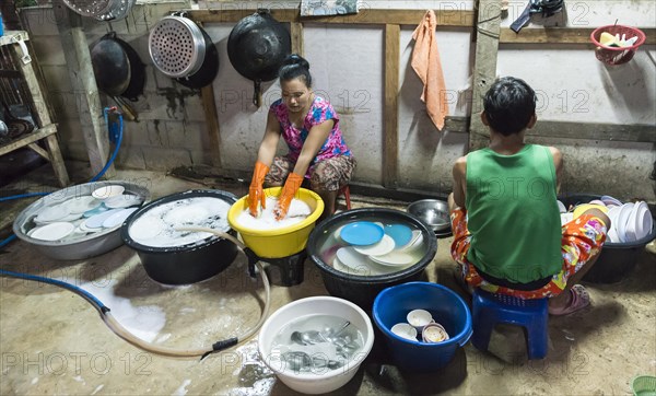 Thai woman washing dishes and pots