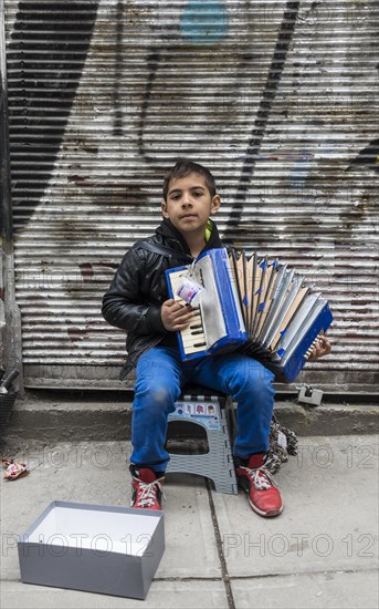 A boy playing the accordion on the road