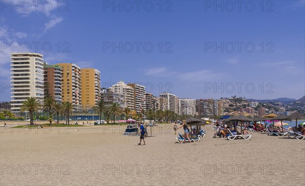 Deck chairs on the beach and skyscrapers behind at Playa de la Malagueta