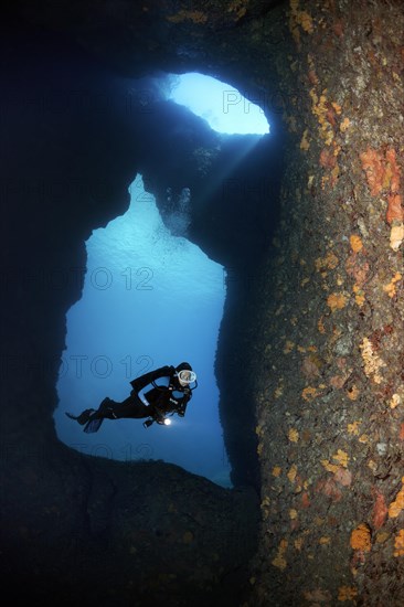 Diver with lamp in a rocky cave