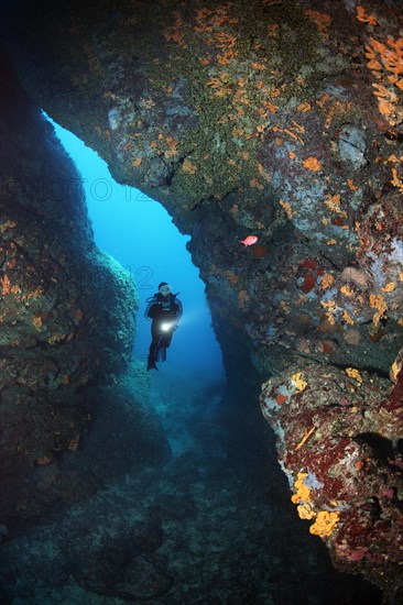 Diver with lamp in rocky cave