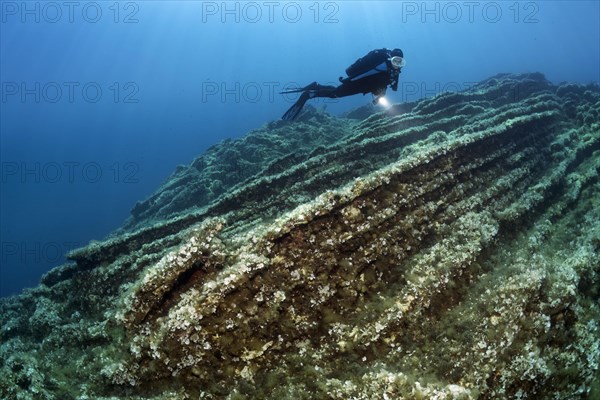 Diver observing layers of rock on shelf