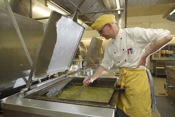 Chef stirring a large cooking vessel