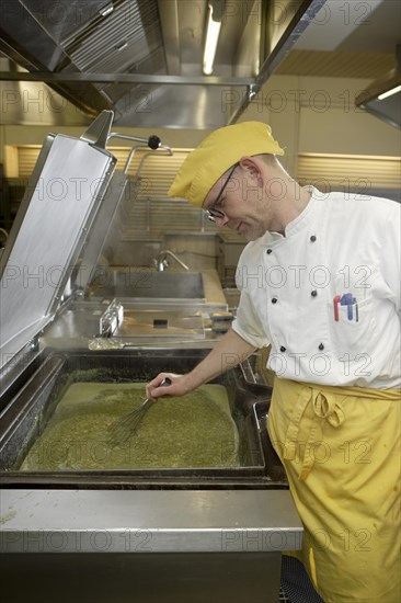 Chef stirring a large cooking vessel