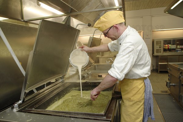 Chef stirring a large cooking vessel