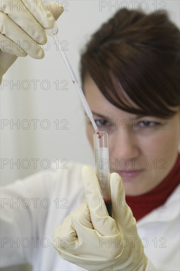 Female laboratory assistant in the laboratory holding a blood sample