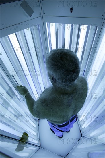 Man standing in an UV phototherapy cabin for UV light therapy at a dermatologist