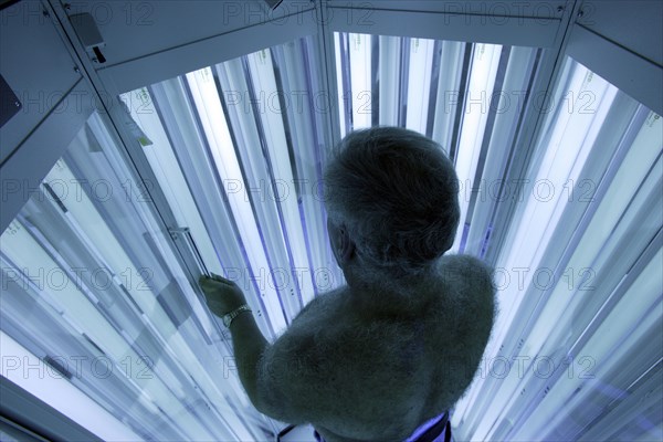 Man standing in an UV phototherapy cabin for UV light therapy at a dermatologist