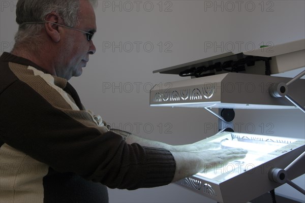 Patient has his hands in a phototherapy box for an irradiation treatment