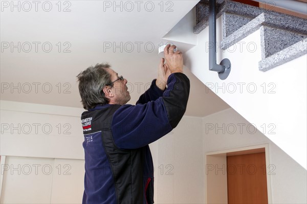 Caretaker with smoke detector in a stairwell