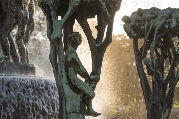 Boy sitting in stylised tree in front of fountain