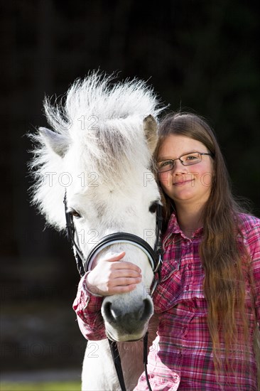 Girl cuddling with a pony