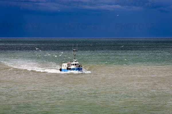Fishing boat in the sea in front of storm front in Saint-Valery-en-Caux
