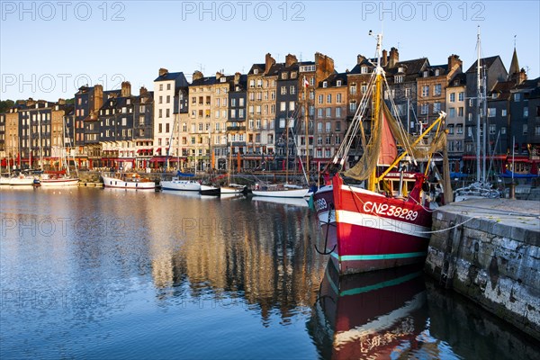 Houses and fishing boats at the old harbor with reflections in calm water