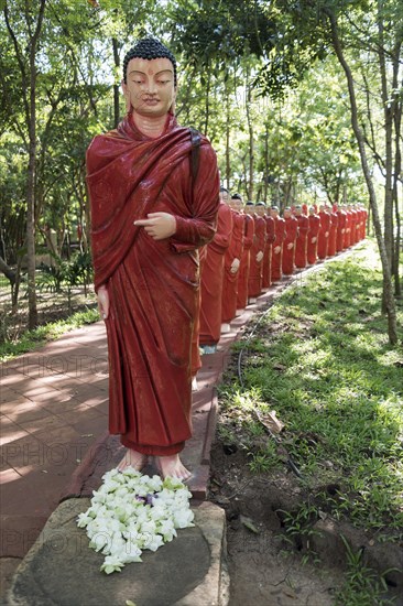 Statues of monks walking behind Buddha