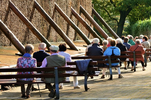 People are sitting in front of the graduation tower with brine deposits in the spa gardens of Bad Sassendorf