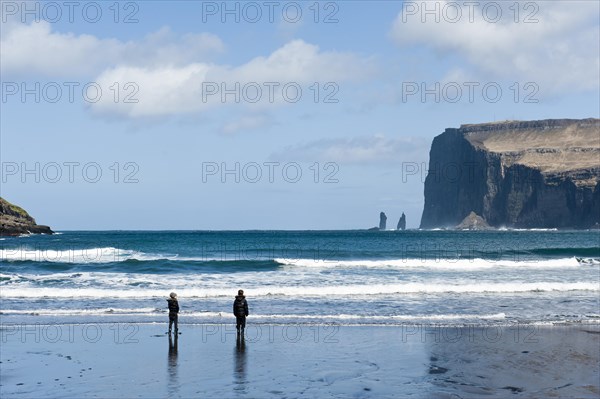Two people on the black sand beach of Tjornuvik