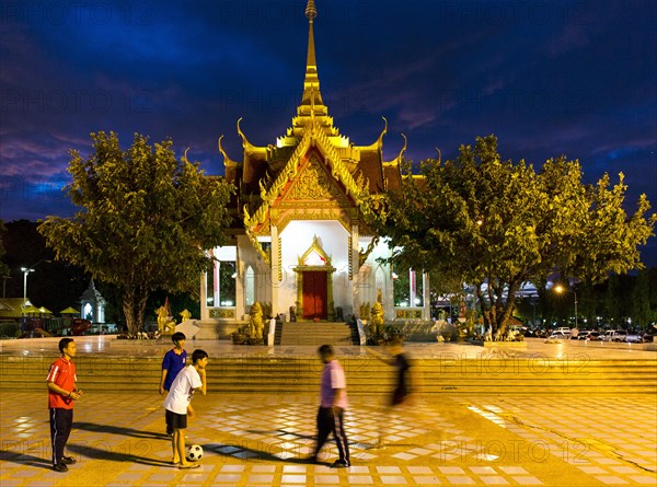 Teenagers playing football in front of the San Lak Muang