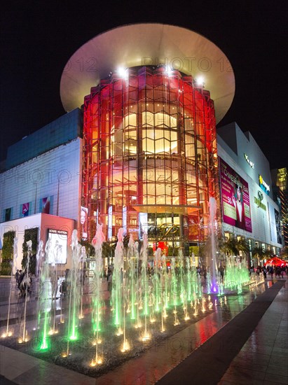 Siam Paragon shopping center at night with fountain in front of the illuminated glass facade