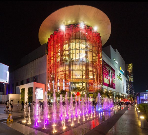 Siam Paragon shopping center at night with fountain in front of the illuminated glass facade