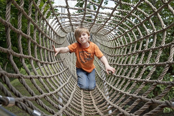 Boy crawling through a rope tunnel