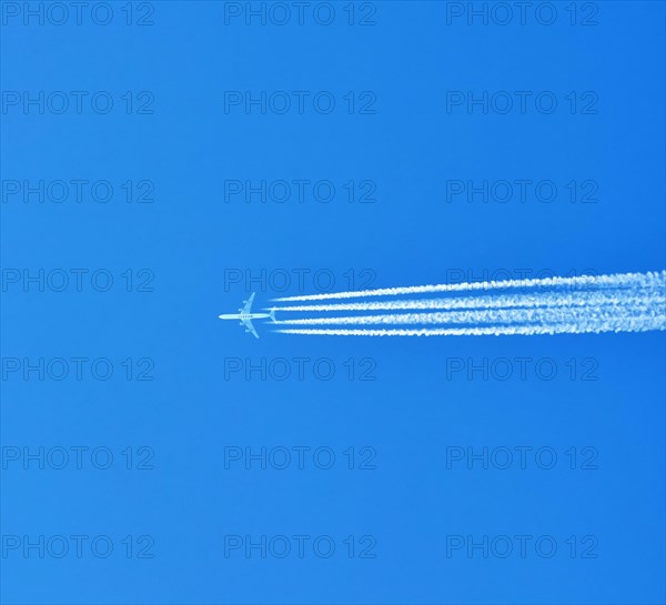 Aibus 380 widebody aircraft of Qatar Airlines with contrails in blue sky