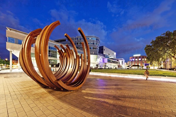 Modern sculpture of Bernar Venet with the inner city in the evening