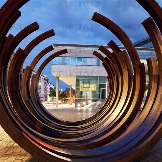 Modern sculpture of Bernar Venet with the inner city in the evening