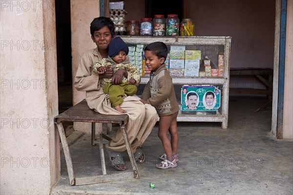 Children sitting in front of a small shop