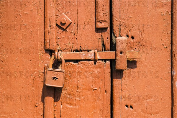 Old painted orange door with a deadbolt