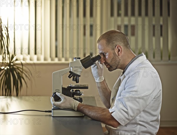 Doctor looking through microscope