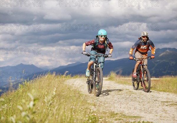 Two mountain bikers with helmets riding on gravel roads