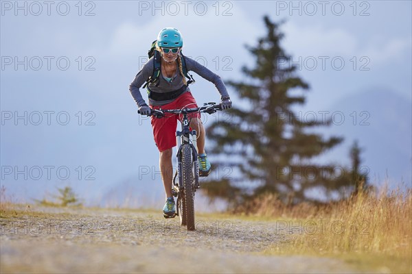 Mountain biker with a helmet riding on a gravel road