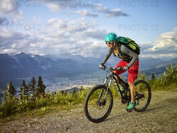 Mountain biker with a helmet riding on a gravel road