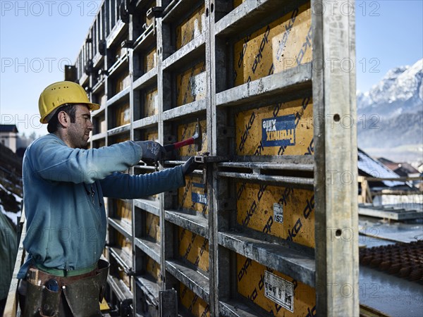 Construction worker hitting connecting element with hammer