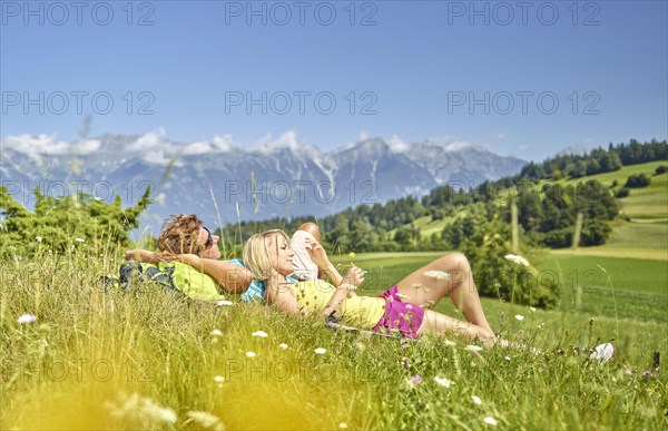 Man and woman lying in a flower meadow with a view of the North Chain