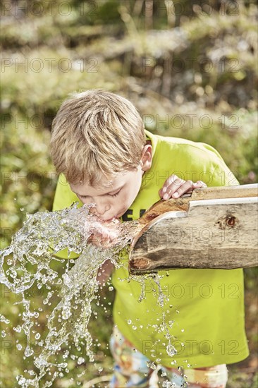 Blond boy drinking water from a fountain