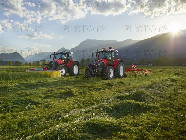 Two tractors mowing and tedding the cut hay