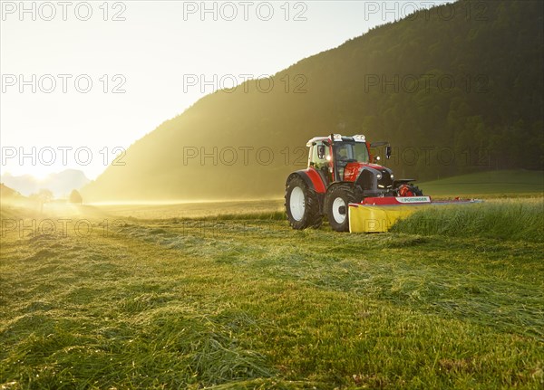 Tractor mowing a field at sunrise