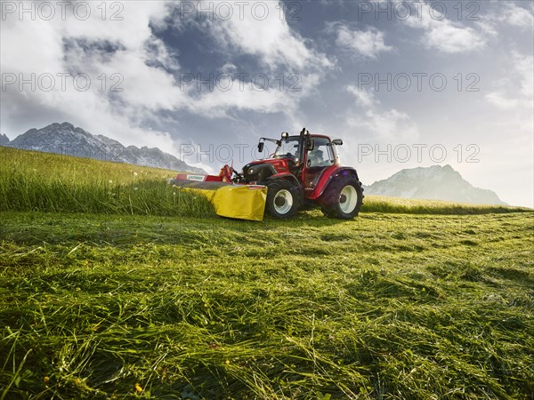 Tractor mowing a field at sunrise