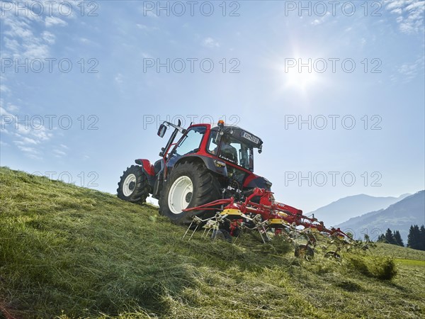 Tractor tedding the freshly cut hay with a tedder
