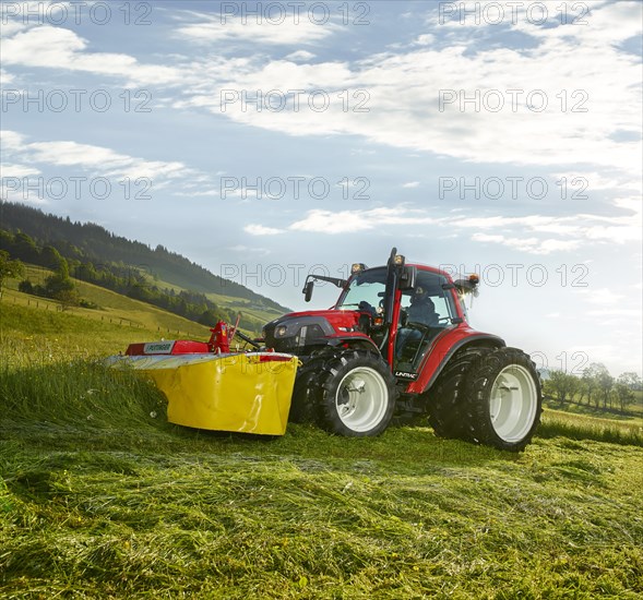 Tractor with dual wheels mowing a field